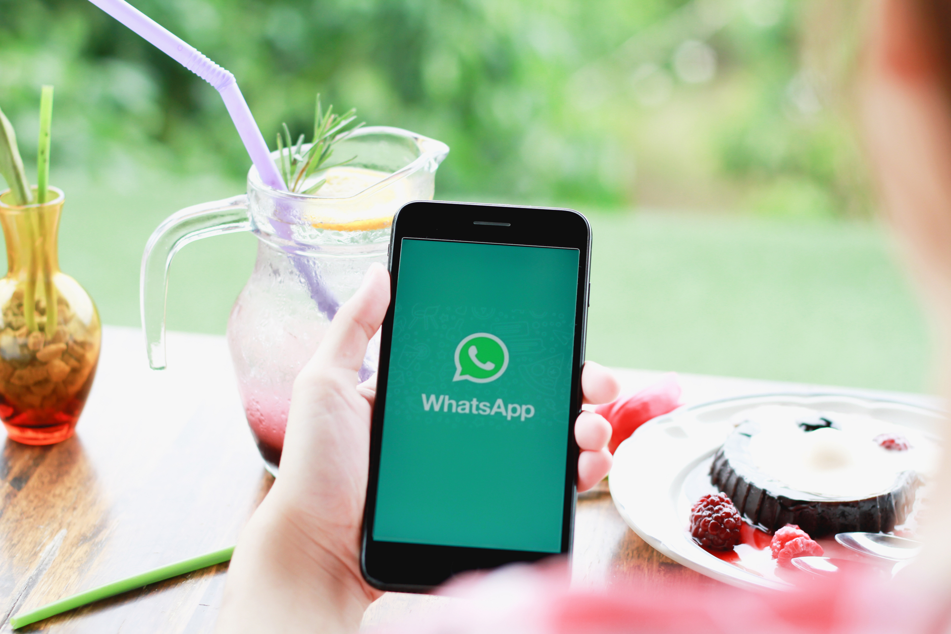 Close-up image of a mobile phone screen featuring the WhatsApp messaging application. Various chat bubbles and timestamps reveal an active conversation history, while the green WhatsApp logo is prominently displayed